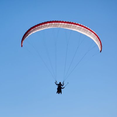 A paraglider soars alone in the endless blue sky. High quality photo