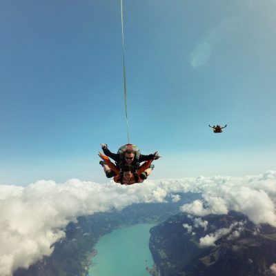 Portrait of tandem skydivers above clouds and landscape